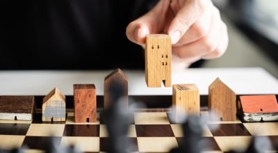 hand-business-man-moving-building-house-models-chess-game (1)